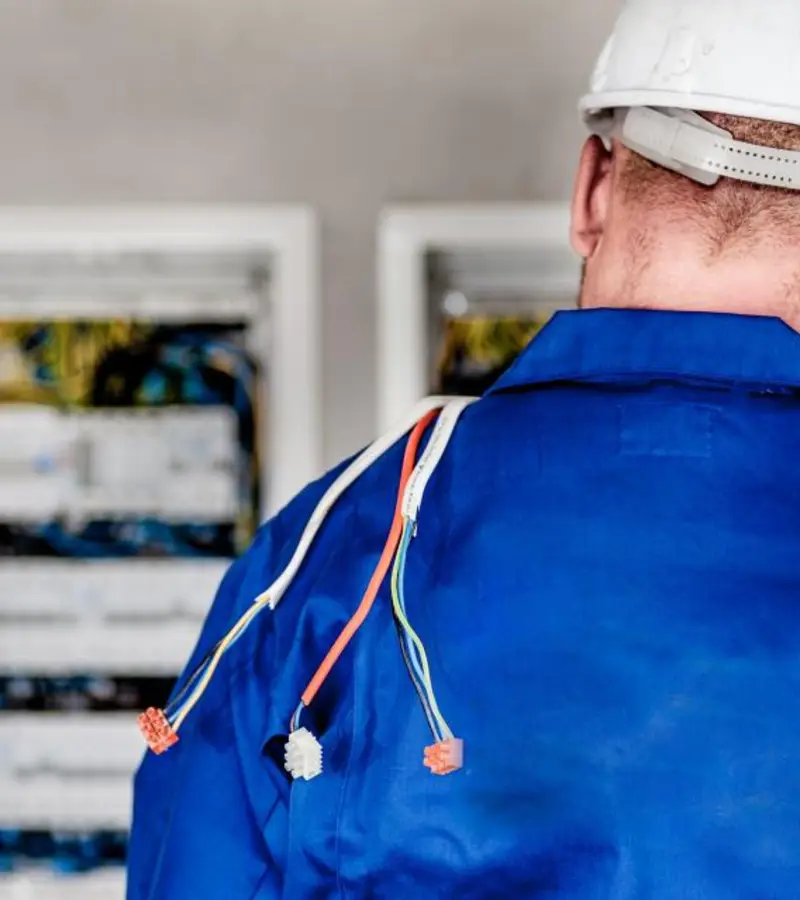 Baretli elektrik teknisyeni dağıtım panosunun başında çalışıyor